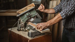 Artigiano che taglia un legno con una sega elettrica