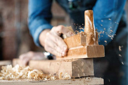 Artigiano che pialla un pezzo di legno