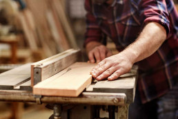 artigiano che sta tagliano un pezzo di legno